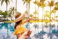 Young couple traveler relaxing and enjoying the sunset by a tropical resort pool while traveling for summer Royalty Free Stock Photo