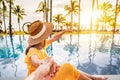 Young couple traveler relaxing and enjoying the sunset by a tropical resort pool while traveling for summer vacation Royalty Free Stock Photo