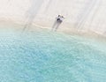 Young couple traveler sitting and relaxing at beautiful tropical white sand beach with wave foam and transparent sea, Summer Royalty Free Stock Photo