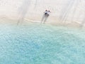 Young couple traveler sitting and relaxing at beautiful tropical white sand beach with wave foam and transparent sea Royalty Free Stock Photo