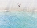 Young couple traveler sitting and relaxing at beautiful tropical white sand beach with wave foam and transparent sea Royalty Free Stock Photo