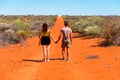 Young couple of travelers holding hands, standing on red sand