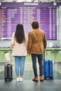 Young couple travelers looking at departure board in airport Royalty Free Stock Photo