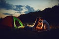 Romantic camping. A young couple sitting by the bonfire