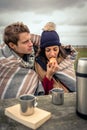 Young couple under blanket eating muffin outdoors in a cold day Royalty Free Stock Photo