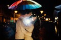 Young couple under an umbrella kisses at night on a city street. Royalty Free Stock Photo