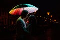 Young couple under an umbrella kisses at night on a city street. Royalty Free Stock Photo