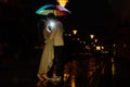 Young couple under an umbrella kisses at night on a city street. Royalty Free Stock Photo