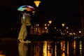 Young couple under an umbrella kisses at night on a city street. Royalty Free Stock Photo