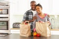 Young Couple Unpacking Shopping In Modern Kitchen