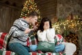 Young couple upset woman and angry man both wearing warm sweaters quarrelling in room decorated for celebrating the new