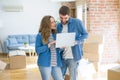 Young couple using computer laptop standing on a room around cardboard boxes, happy for moving to a new apartment Royalty Free Stock Photo