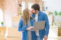Young couple using computer laptop standing on a room around cardboard boxes, happy for moving to a new apartment Royalty Free Stock Photo