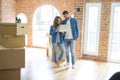 Young couple using computer laptop standing on a room around cardboard boxes, happy for moving to a new apartment Royalty Free Stock Photo