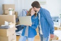 Young couple using computer laptop standing on a room around cardboard boxes, happy for moving to a new apartment Royalty Free Stock Photo