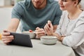Young couple using digital tablet enjoying breakfast in kitchen Royalty Free Stock Photo