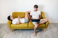 Young couple using gadgets while relaxing at home