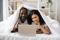 Young couple using laptop while lying in bed Royalty Free Stock Photo