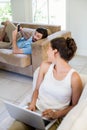 Young couple using laptop and mobile phone in living room Royalty Free Stock Photo