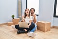 Young couple using laptop at new home amazed and surprised looking up and pointing with fingers and raised arms Royalty Free Stock Photo