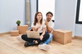 Young couple using laptop at new home pointing aside worried and nervous with forefinger, concerned and surprised expression Royalty Free Stock Photo