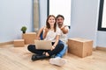 Young couple using laptop at new home smiling cheerful offering palm hand giving assistance and acceptance Royalty Free Stock Photo