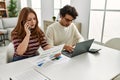 Young couple using laptop and talking on the smartphone sitting on the table at home Royalty Free Stock Photo