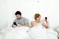 young couple using mobile phone in bed ignoring each other in relationship communication problems Royalty Free Stock Photo