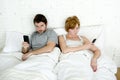 young couple using mobile phone in bed ignoring each other in relationship communication problems Royalty Free Stock Photo