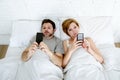 young couple using mobile phone in bed ignoring each other in relationship communication problems Royalty Free Stock Photo