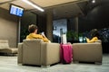 Young couple using mobile phones while waiting for the plane in the airport waiting room. Couple sitting with yellow clothes and Royalty Free Stock Photo