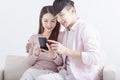 Young couple using smart phone , browsing internet, chatting online, relaxing on sofa at home Royalty Free Stock Photo