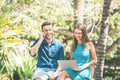 Young couple using smartphone and computer while sitting in a park outdoor - Handsome man having a phone call Royalty Free Stock Photo