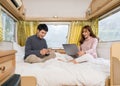 Couple using smartphone and laptop computer on bed of a camper RV van motorhome Royalty Free Stock Photo