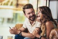 Young couple using a smartphone and smiling while sitting in the cafe Royalty Free Stock Photo