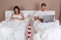 Young couple using tablet and computer in bed. Royalty Free Stock Photo