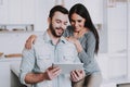 Young Couple Using Tablet PC in White Kitchen. Royalty Free Stock Photo