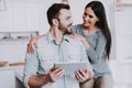 Young Couple Using Tablet PC in White Kitchen. Royalty Free Stock Photo