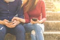 Young couple using their smartphones are sitting in a park, which conveys the concepts of technology social media Royalty Free Stock Photo