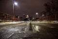 Young couple walking across a river bridge in the city at night in winter