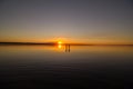 Young couple is walking away in the water on summer beach. Sunset over the sea.Two silhouettes against the sun. Just married Royalty Free Stock Photo