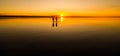 Young couple is walking away in the water on summer beach. Sunset over the sea.Two silhouettes against the sun. Just married Royalty Free Stock Photo