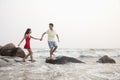 Young couple walking on the beach walking over rocks holding hands Royalty Free Stock Photo