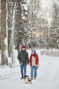 Young couple walking dog in winter forest Royalty Free Stock Photo