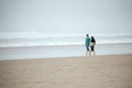 Young couple walking on empty beach next to ocean Royalty Free Stock Photo