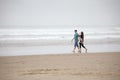 Young couple walking on empty beach next to ocean Royalty Free Stock Photo