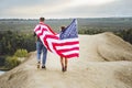 Young couple walking flying American flag in nature. Independence Day, lifestyle, travel concept Royalty Free Stock Photo