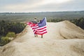 Young couple walking flying American flag in nature. Independence Day, lifestyle, travel concept Royalty Free Stock Photo