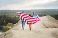 Young couple walking flying American flag in nature. Independence Day, lifestyle, travel concept Royalty Free Stock Photo