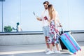 Young couple walking in front of an airport terminal building, pulling suitcases Royalty Free Stock Photo